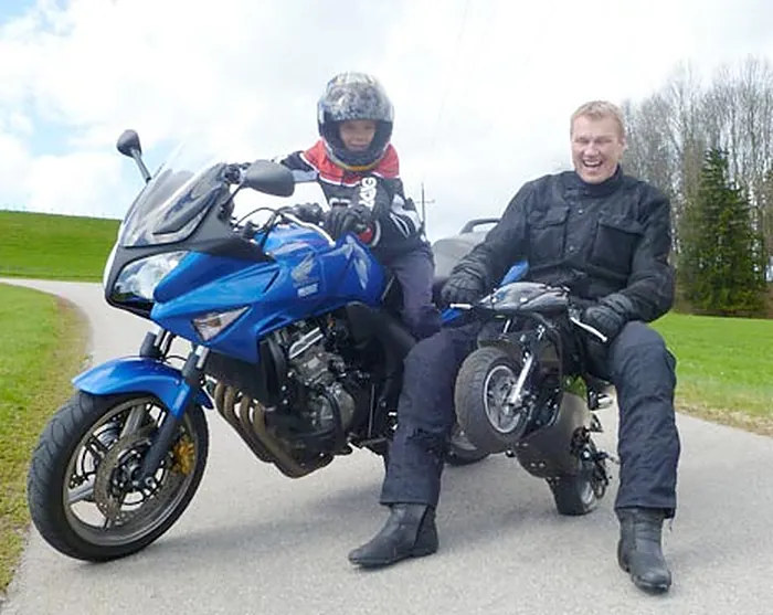 Fahrlehrer Andreas Gutbrod in Motorradkleidung auf seinem Motorrad, daneben ein Fahrschüler mit Helm