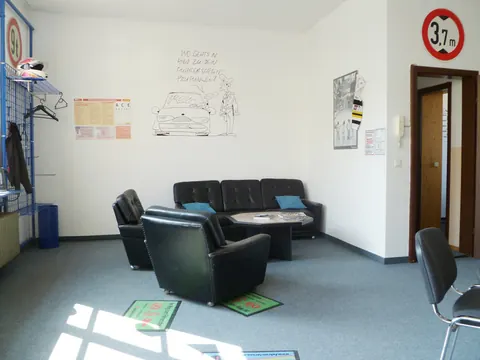 Heller Unterrichtsraum mit Sitzecke, Schildern und Lernplakaten